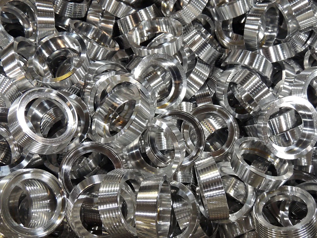 A bin of threaded aluminum rings machined by PrecisionForm